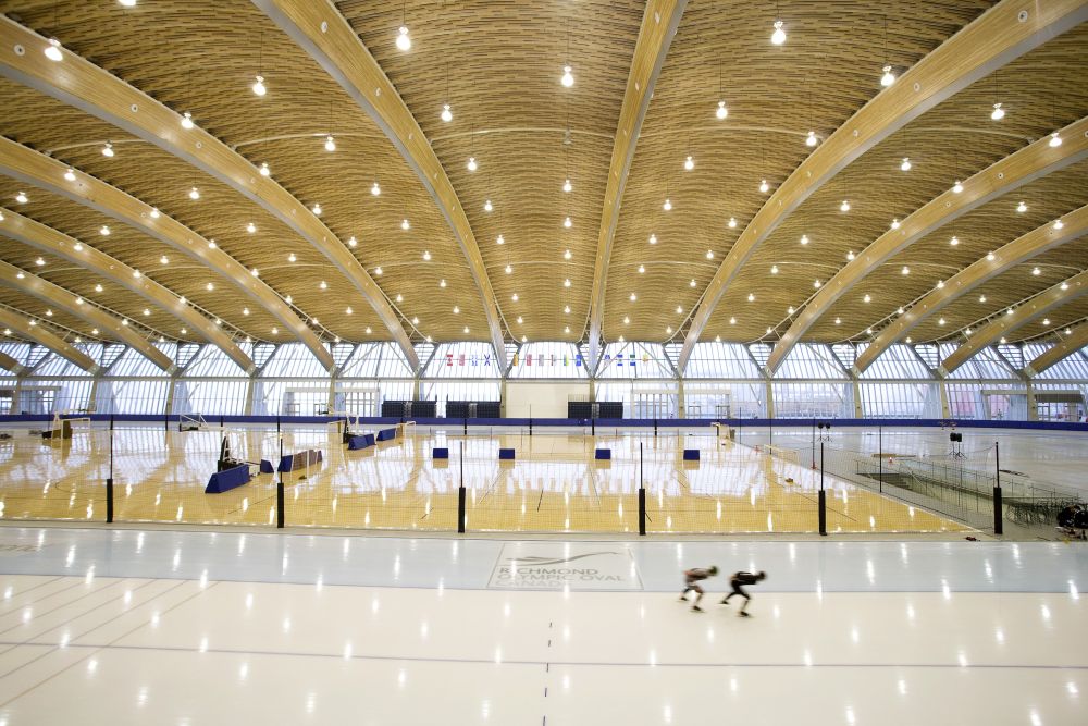 Two skaters are on the speed-skating track while the inside the track is set up with multiple futsal fields. This shows how the flexible space allows for combined sports, recreation and community uses simultaneously.